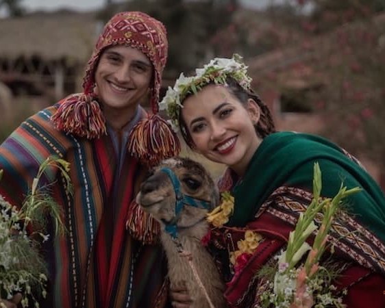 Couple in traditional Andean dress with a baby alpaca